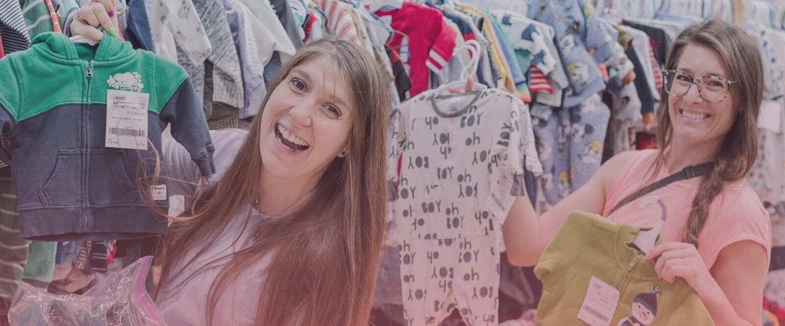 A mom and her child hug in between two rows of little girl clothes