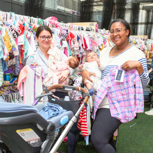 A mom and grandmother stand beside a rack of clothing at a JBF sale in Texas.